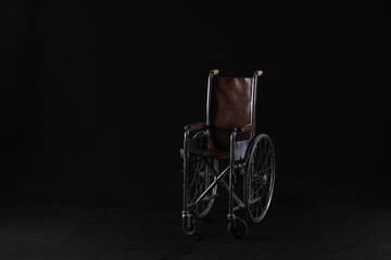 Wall Mural - scary vintage wheelchair on black background