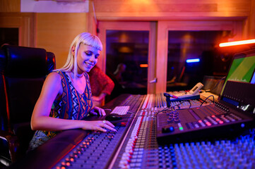 Woman music producer and engineer working at the soundboard in a music studio