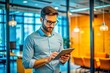 © ivatekstudio - Photo a handsome young in glasses and a shirt stands in the office at the tablet.
