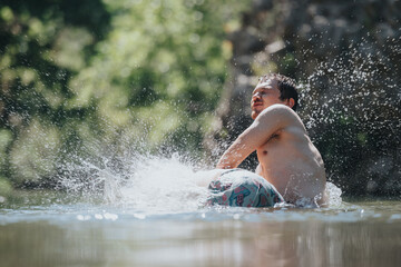 A man experiences the joy of swimming in a clear river, surrounded by nature and splashing water. Captures the essence of summer fun and freedom.