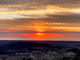 bright orange and pink sunset seen from top of mountain overlooking city and ocean