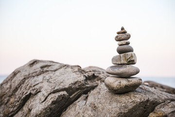 Sticker - serene beach scene with smooth rocks stacked in a balanced formation. The tranquil atmosphere evokes a sense of zen, harmony, and peace, symbolizing balance and mindfulness in nature