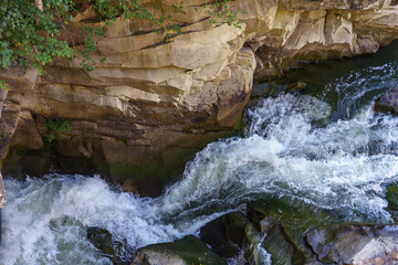 Texture of rapid river with fresh cold water flowing through mountain rocks with foam and bubbles