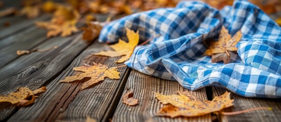 Close up of wooden table with blue and white checkered cloth and autumn foliage for Oktoberfest banner empty space for design