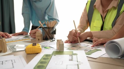 Wall Mural - Smart architect and safety engineer discussion about building blueprint on table with architectural document, measurement tools and wooden block scatter around at modern office. Closeup. Delineation.