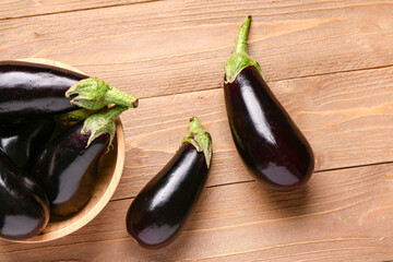 Bowl with fresh eggplants on wooden background