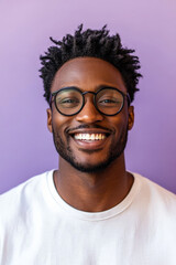 Young African American man with glasses, smiling brightly with confidence and joy, standing against a light lavender background.