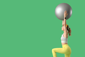 Sticker - Young sporty woman in headphones training with fitness ball on green background