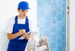 © JackF - Portrait of man builder in blue construction overalls with documents in hands checks quality of completed repairs in apartment