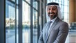 © Jakkarin - Successful Middle Eastern Businessman Smiling Confidently in Elegant Office Space with Natural Light
