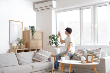 Sticker - Young man switching  on air conditioner at home