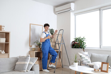 Male worker repairing air conditioner in room