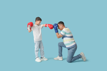 Canvas Print - Cute little boy with his father in boxing gloves on blue background