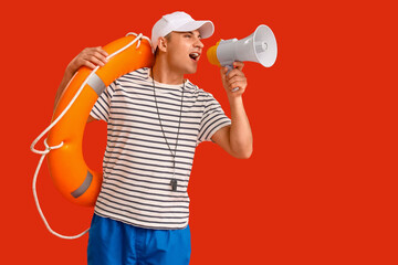 Wall Mural - Male lifeguard with ring buoy and megaphone screaming on red background