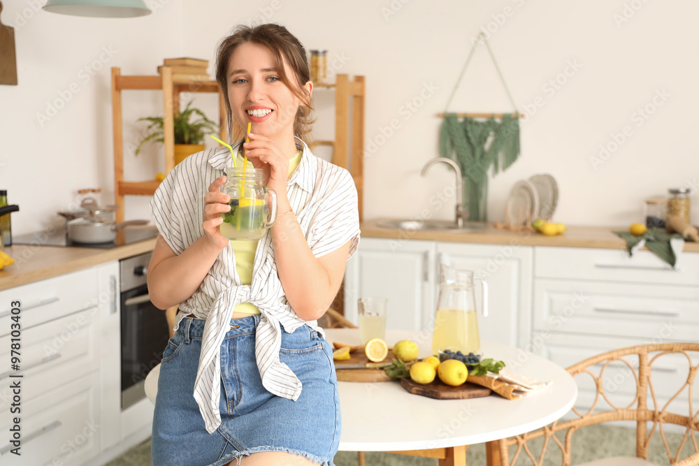 Young woman with tasty lemonade in kitchen