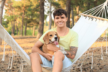 Sticker - Young man with Beagle dog sitting in hammock outdoors