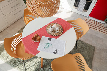 Poster - Eyeglasses with newspaper and muffins on dining table in kitchen, top view