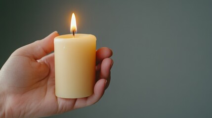 Wall Mural - A person holding a lit candle in their hand with grey background, AI