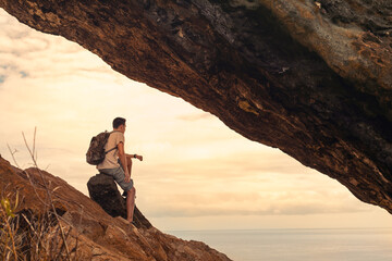 Young male hiker on the edge of a mountain cliff looking out into the horizon	