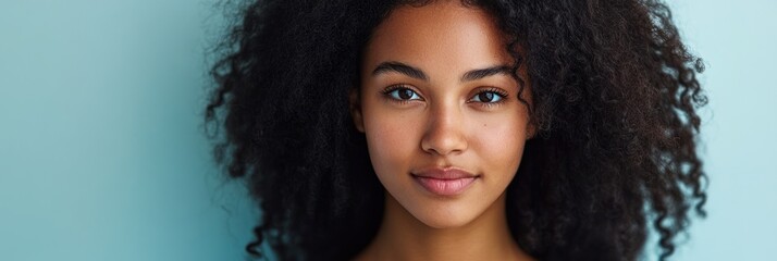 Canvas Print - A close-up portrait of a young woman with curly hair against a light blue background.