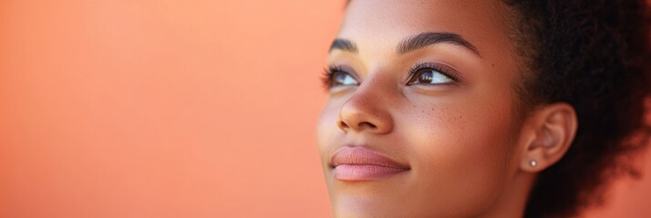 Canvas Print - A young woman gazes thoughtfully, showcasing a serene expression against a warm background.