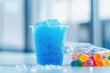 © Boinah - A cup of blue slush ice next to colorful gummy candies on a table.