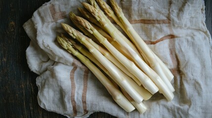 Fresh white asparagus spears, peeled and ready to be cooked, placed on a linen cloth for a rustic presentation.