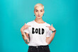 © Malambo/peopleimages.com - Pointing, tshirt and portrait of woman in studio for feminism, gender equality or empowerment. Fashion, bold print and gen z female person with quote on clothes for casual style by blue background.