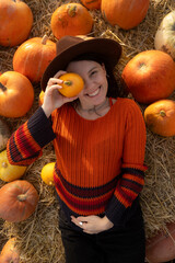 Wall Mural - Woman lying on hay with pumpkins during autumn