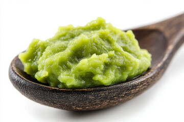 A wooden spoon with green-colored, homemade wasabi paste on a white background, close-up.