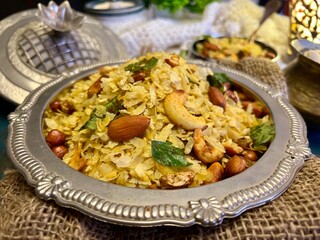 Side Angle shot of Chivda namkeen in a silver plate garnished with cashew and peanut.