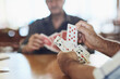 © SometimesNever/peopleimages.com - Card, game and people hands in retirement home with senior care, playing and fun on table. Cognitive, memory and activity in friends group with hobby, relax and poker for brain engagement and support