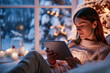 © eshana_blue - Woman is relaxing on her couch using a digital tablet on christmas eve with snow falling outside