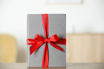 Hardcover book with ribbon as gift on wooden table indoors