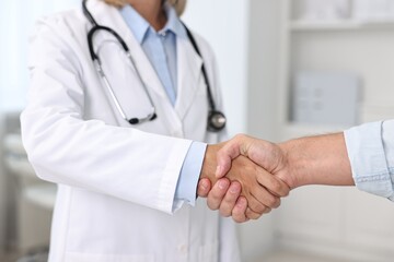 Wall Mural - Doctor shaking hands with patient in hospital, closeup