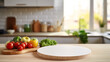 © vectorhot - Kitchen table with a white round empty cutting board, vegetables, window, blurred white kitchen in the background. Round podium, presentation, advertising, mockup for products and goods.