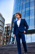 © Alex Vog - Strong man businessman in blue suit and white shirt in business district at skyscraper, looking away. Full length of business male near building corporate company in financial area. Copy ad text space