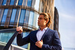 © Alex Vog - Portrait of confident man businessman in blue suit standing near car in business district at skyscrapers backdrop, strong looking away. Business male posing in urban financial area. Copy ad text space