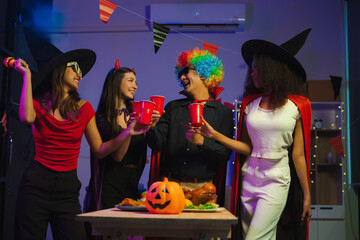 Dinner and group of people celebrating together at Halloween party. Friends are happy and celebrating with food, wine and friendship of love and cheers of champagne at the event.