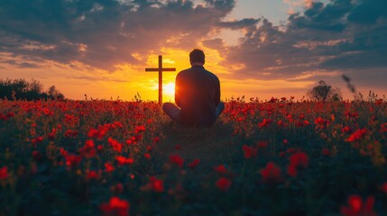 Wall Mural - Man kneeling near the wooden Christian cross on a nature meadow grass field at sunset.