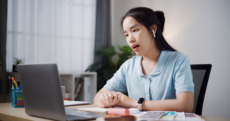 Portrait of Female freelancer wear wireless headphones explaining project in online meeting with team members via laptop in home office. Working from home, Remote working.