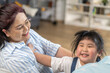 © Art_Photo - Asian grandmother smiling and playing with young granddaughter at home, happy family bonding love and affection, joyful asian senior woman enjoying playful moment with granddaughter in living room
