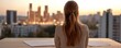 © ParinApril - A woman gazing at a city skyline during sunset, contemplating her next creativity or business move from a modern workspace.