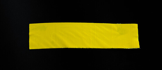 yellow tapes on black background. Torn horizontal and different size yellow sticky tape, adhesive pieces.