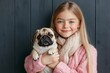 © Rebecca Jestico - Girl holding pet pug dog, wrinkled face, pedigree breed. Purebred puppy canine, adorable animal.