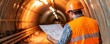 © ParinApril - A construction worker examining plans inside a tunnel, wearing safety gear for a project, highlighting dedication to engineering.