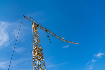 Construction crane towering over a bright blue sky at the site