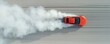 © ParinApril - Aerial view of a vibrant orange car performing a drift on a sandy terrain, creating a cloud of smoke.
