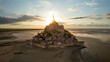 © AmazingAerialAgency - Aerial view of mont saint michel at sunset with beautiful architecture and scenic coastline, mont saint michel, france.
