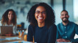 © Olha Havelia - A happy business team sits at a table with graphs and documents in a modern office, laughing together while looking at the camera and smiling during a meeting or training session.